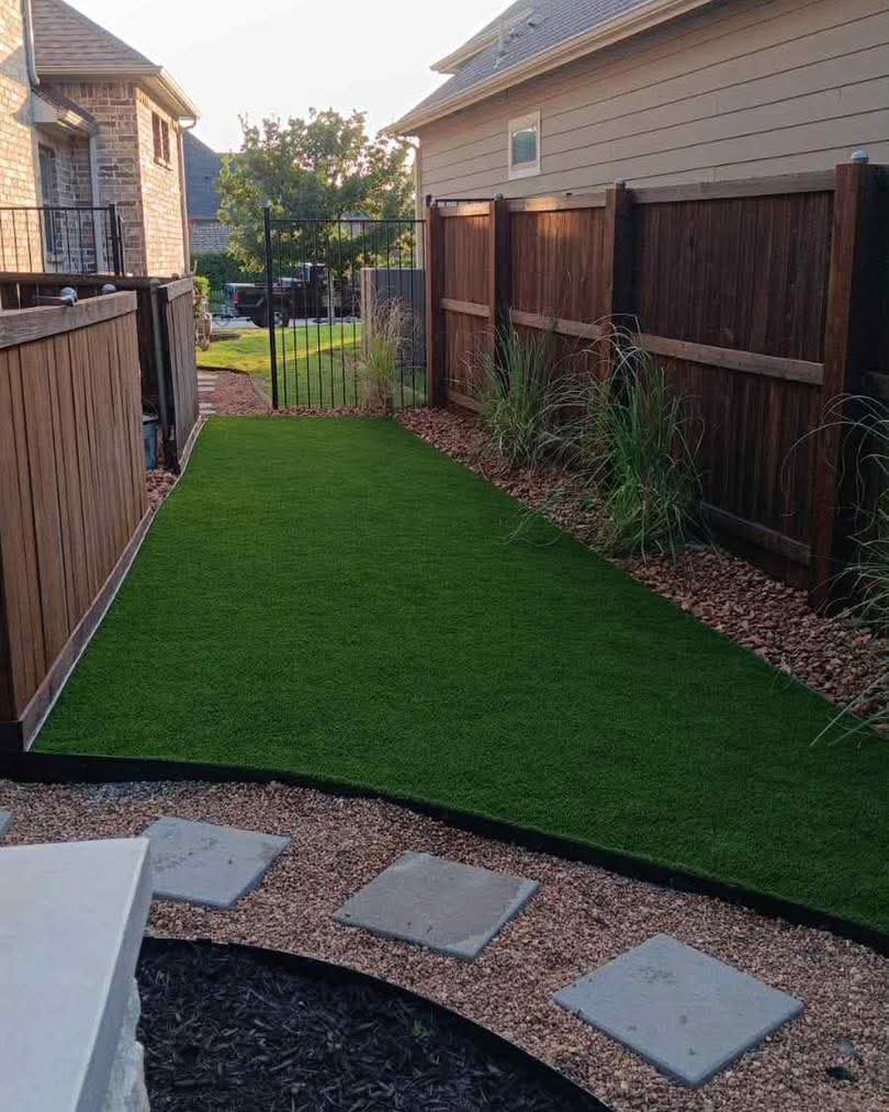 A side yard with artificial turf and gravel